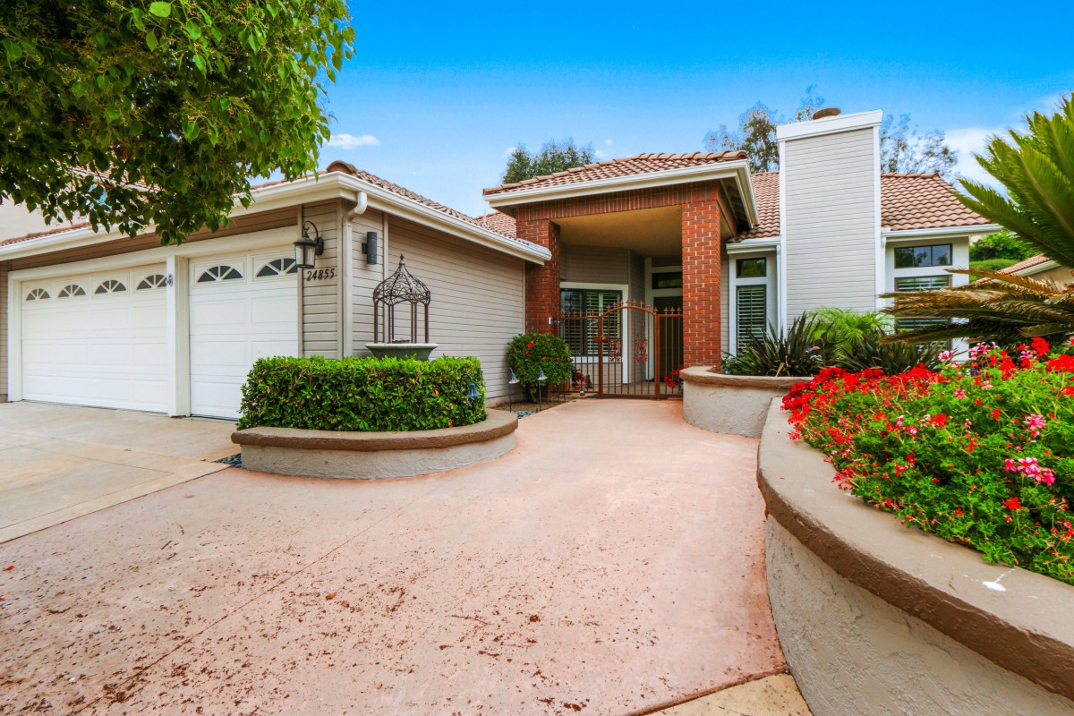 A well-maintained residential house with a spacious driveway and lush garden.