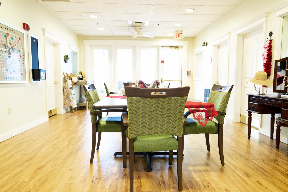 A well-lit dining area with a table and chairs on a wooden floor, creating a welcoming community space.