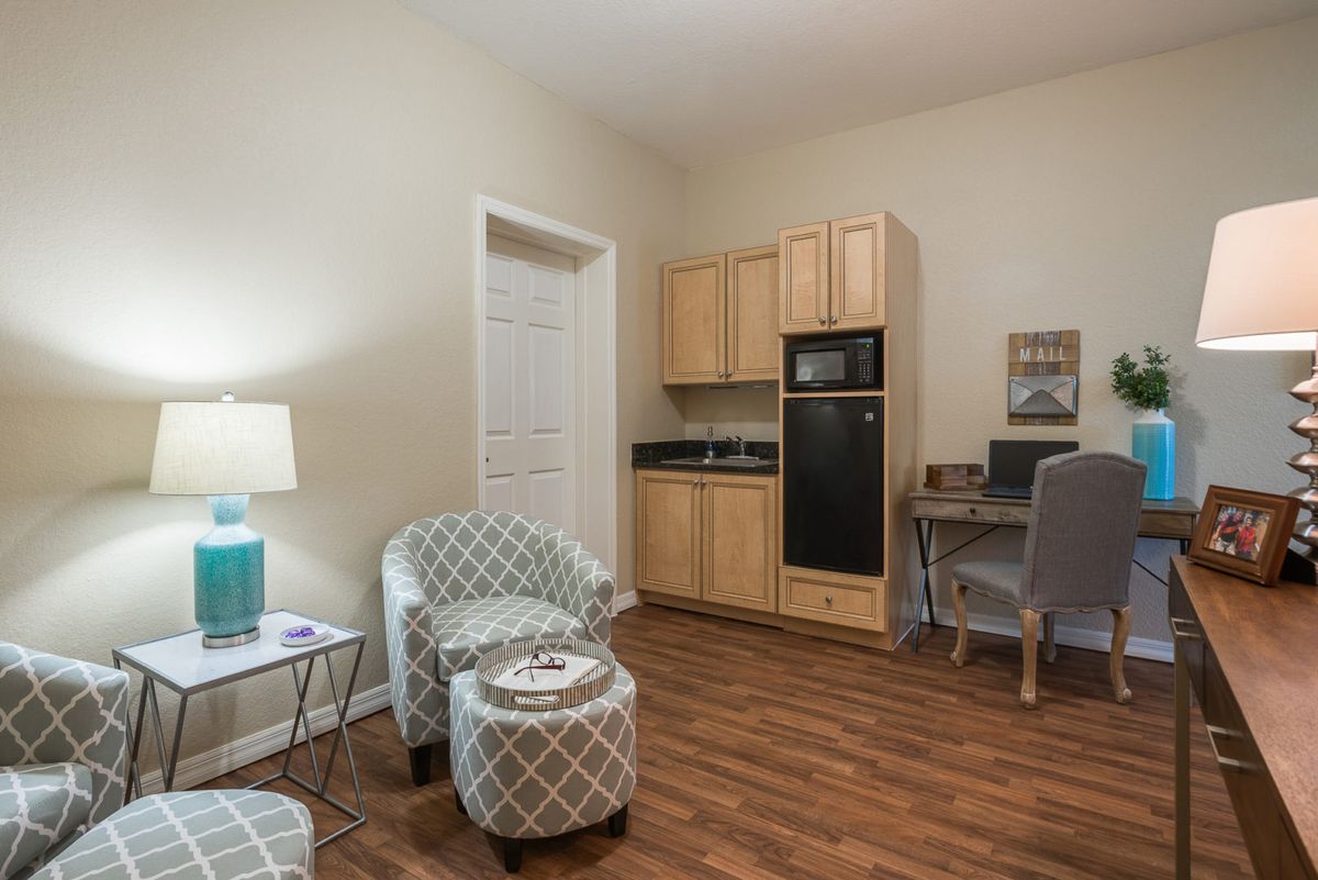 A cozy living space with a small kitchenette, seating area, and desk.