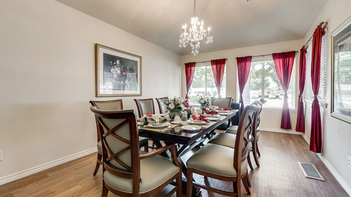 A beautifully decorated dining room with a large table, elegant chairs, and a chandelier.
