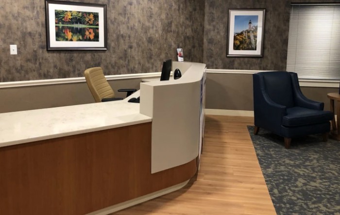 A modern reception desk in an office setting with artwork on the walls.
