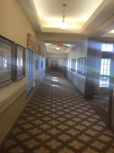 A well-lit hallway featuring decorative walls and a patterned carpet, lined with framed pictures.