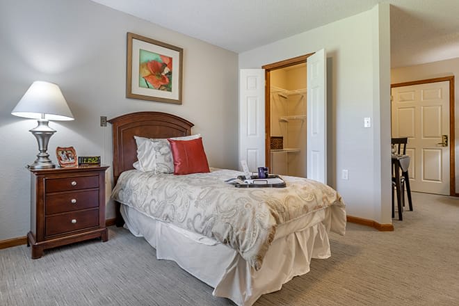 A cozy bedroom with a single bed, decorative pillows, and artwork above the headboard.
