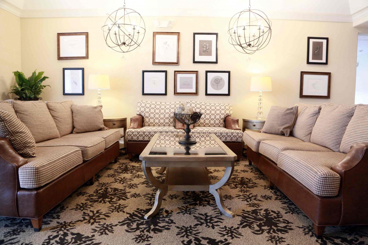 A modern living room with sofas, a central coffee table, wall art, and stylish chandeliers.