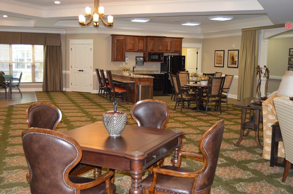 A cozy dining area with a kitchen in the background, featuring wooden tables and chairs.