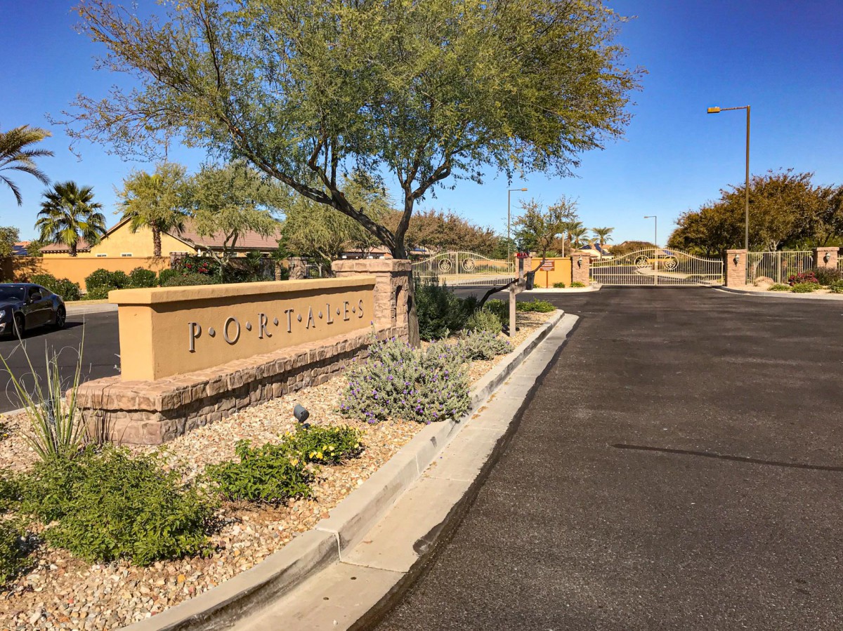 Entrance to a gated community with landscaped surroundings and desert plants.