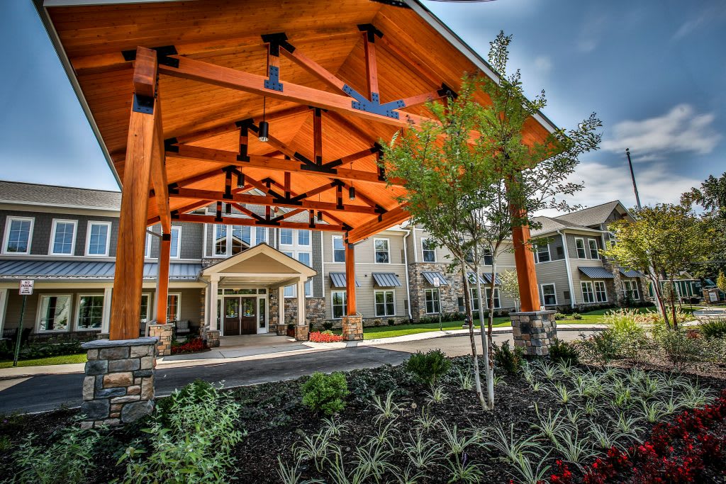 A modern building entrance with a striking wooden canopy and well-maintained landscaping.