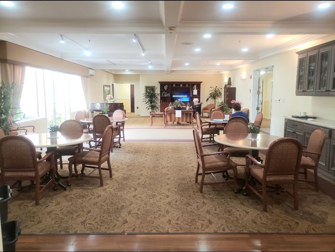 A spacious dining room with several tables and chairs, illuminated by overhead lighting.