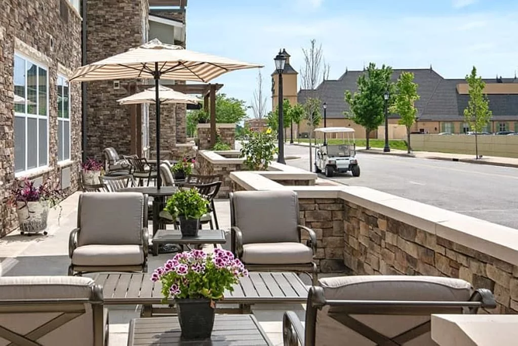 A cozy outdoor patio with comfortable seating and umbrellas, overlooking a quiet street.