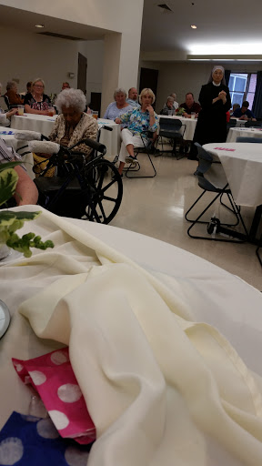A view of a gathering setting with tables and attendees, including individuals in wheelchairs.