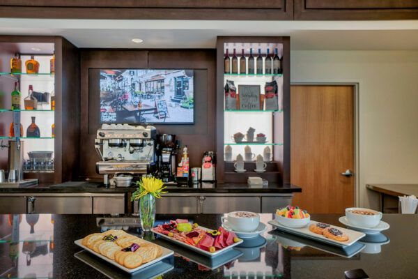 A cafe counter with a coffee machine, desserts, and drinks on display.