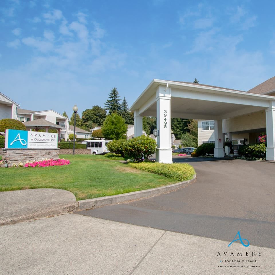 A building entrance with a driveway and well-maintained lawn under a clear sky.