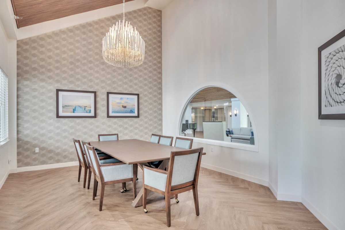 A modern dining room featuring a wooden table, elegant chairs, a stylish chandelier, and decorative wall art.