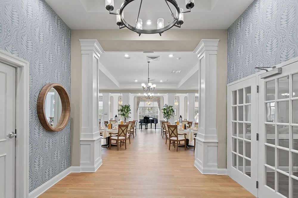 An elegant dining room with decorative columns and chandeliers, featuring a hardwood floor and formal dining setup.