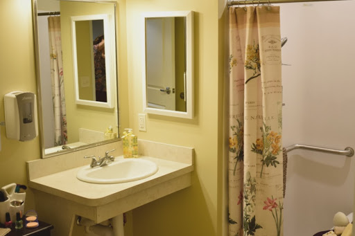 A well-lit bathroom featuring a sink with two mirrors and a decorative shower curtain.