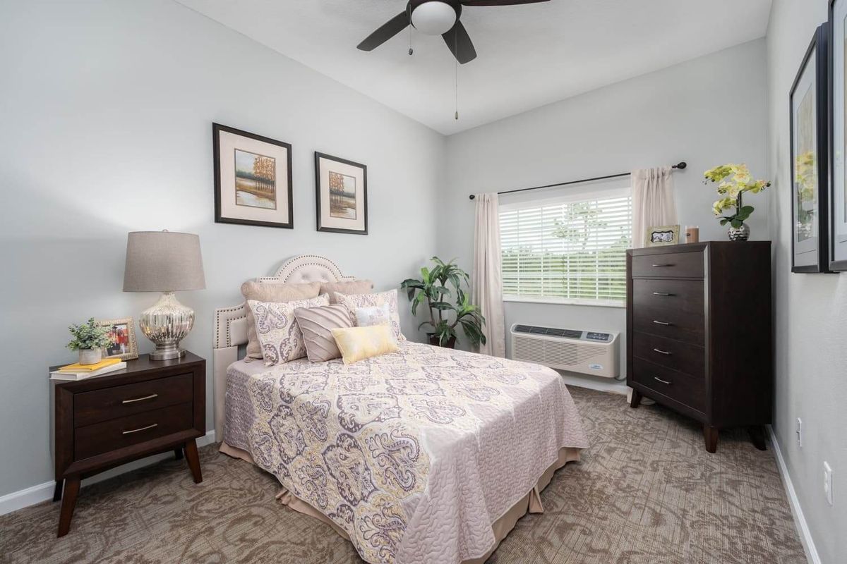 A cozy and elegantly decorated bedroom with a bed, two nightstands, a dresser, and a window letting in natural light.