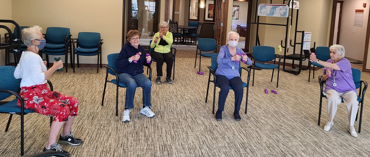 Seniors participating in a seated exercise class indoors.