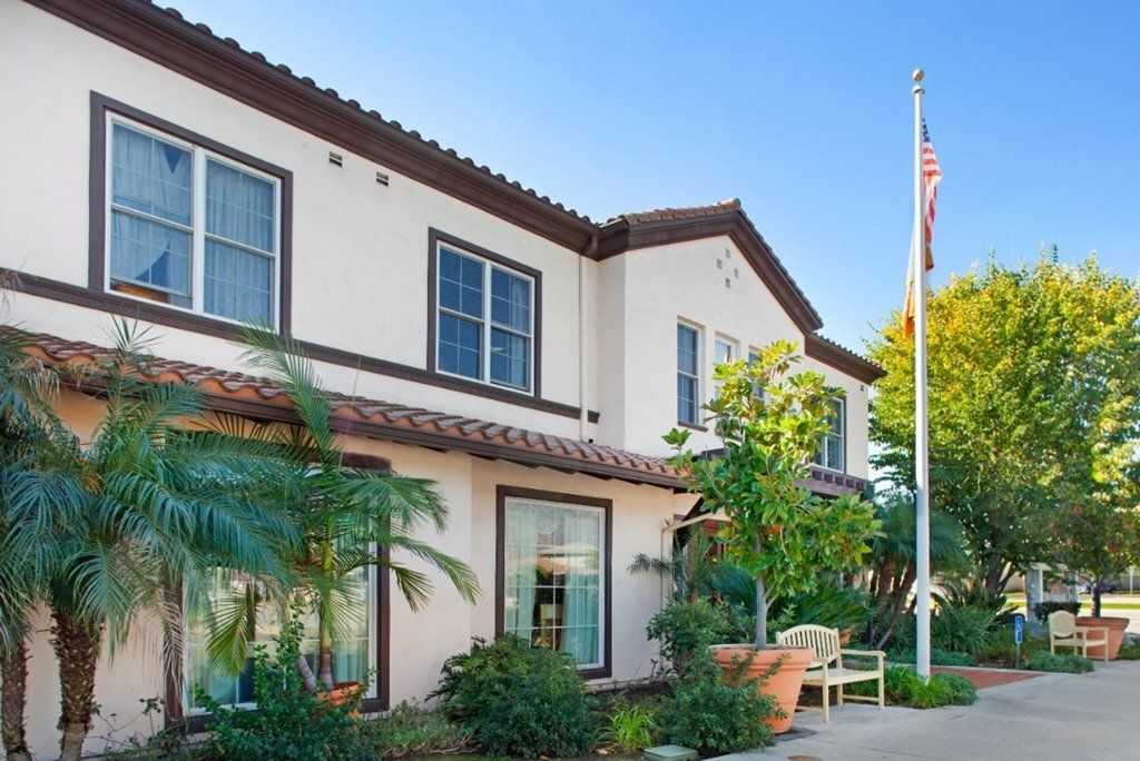 White two-story house with a garden and flag outside.