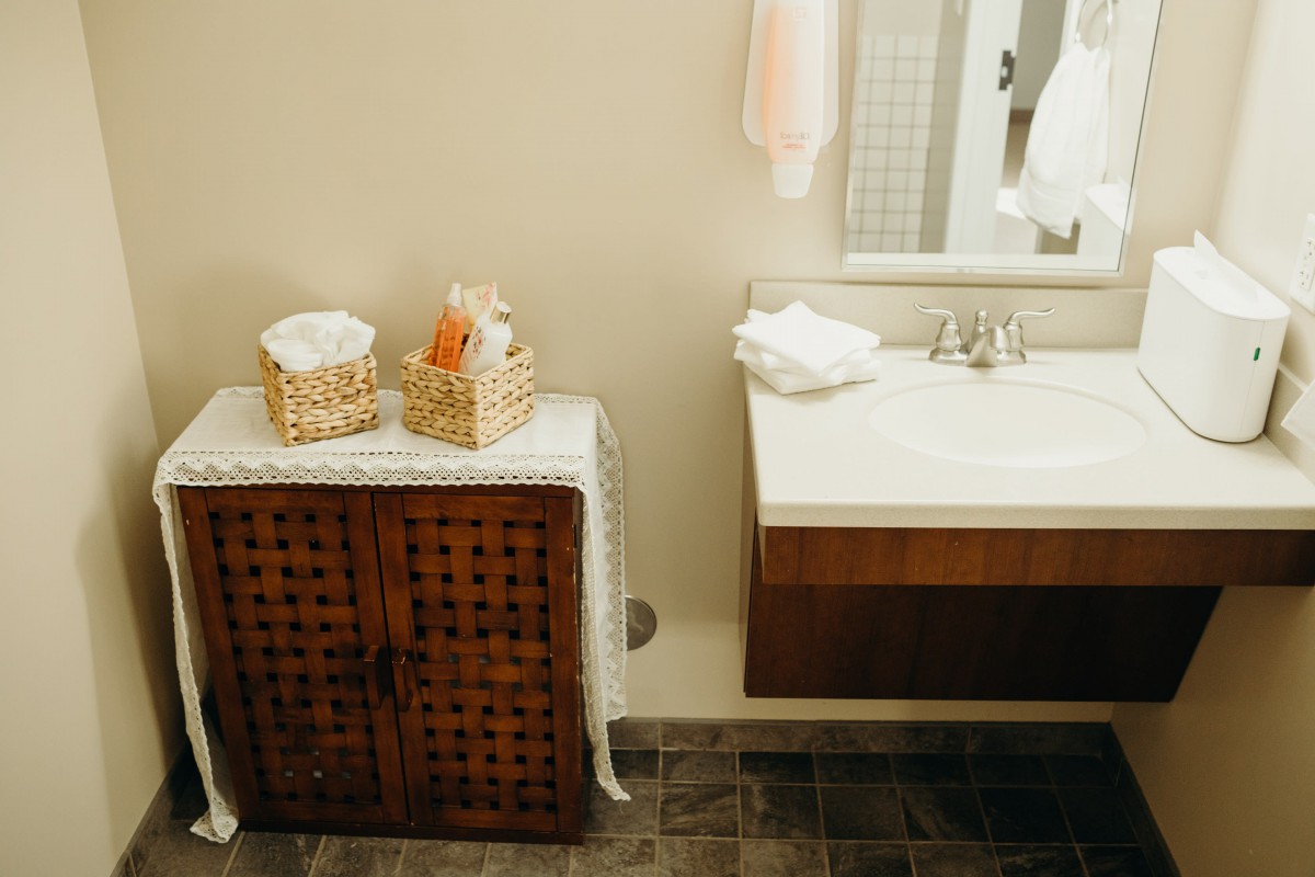A cozy bathroom with a wooden cabinet, baskets of towels, and a modern sink.
