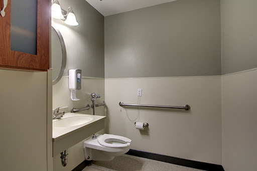 A clean and accessible restroom featuring a toilet, sink, and hand dryer.