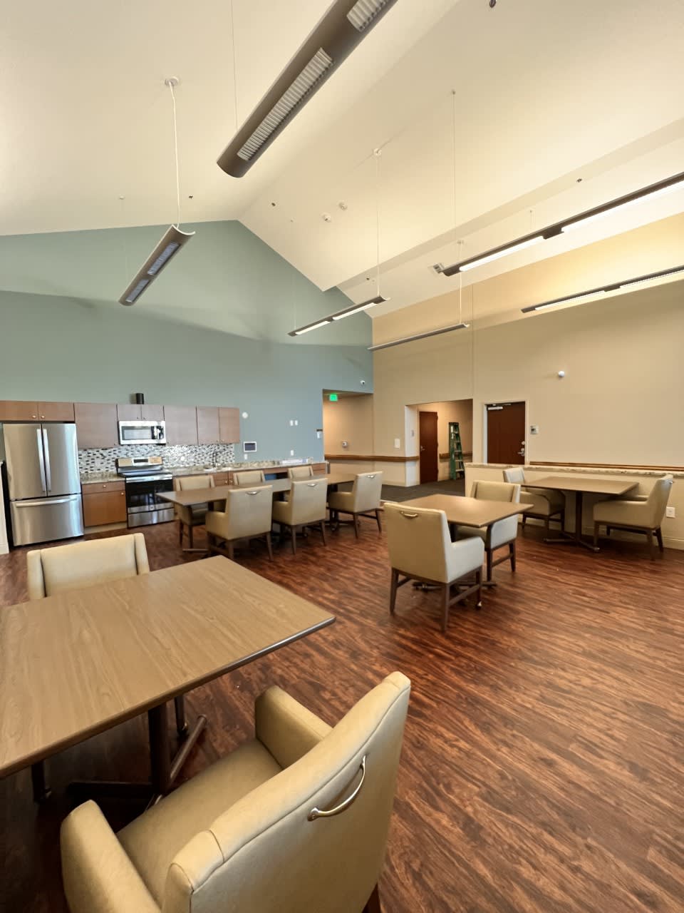 A modern kitchen and dining area with tables, chairs, and a wooden floor.