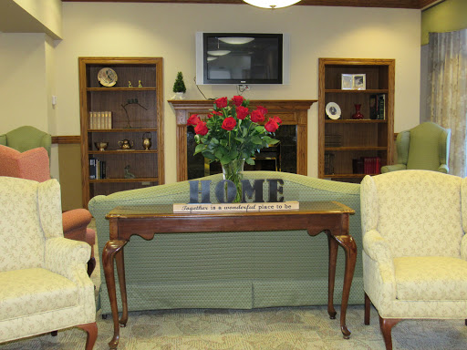 A cozy living room setup featuring a floral centerpiece, comfortable seating, and shelves adorned with decorative items.
