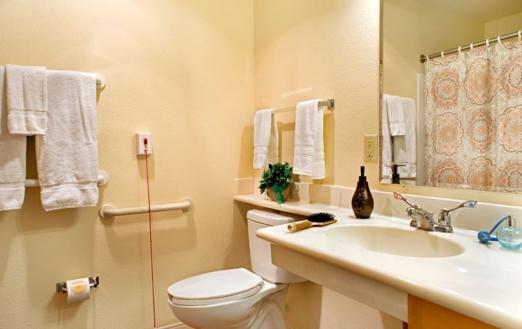 A clean and well-organized bathroom with a toilet, sink, mirror, and towels.