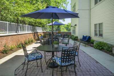 A cozy outdoor patio with tables and chairs under large blue umbrellas.