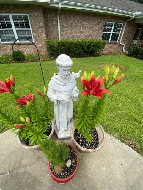 A garden statue surrounded by vibrant lilies in a well-tended lawn.