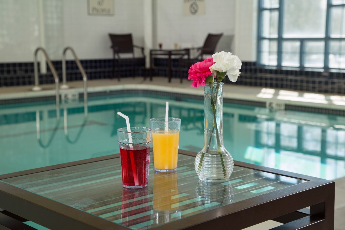 Refreshing drinks and flowers by an indoor pool.