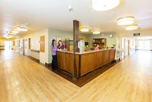A welcoming reception area in a healthcare facility, featuring staff members at the front desk.