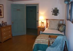 A cozy bedroom with a bed, nightstand, and warm lighting.