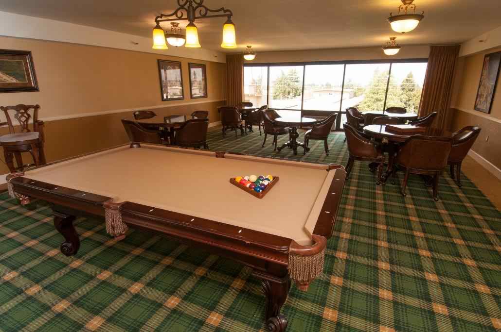 A cozy game room featuring a pool table and comfortable seating with large windows offering a view.