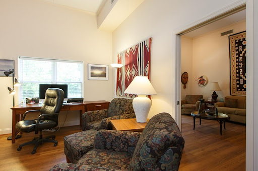 A cozy living room featuring comfortable seating, a lamp, and decorative artwork.
