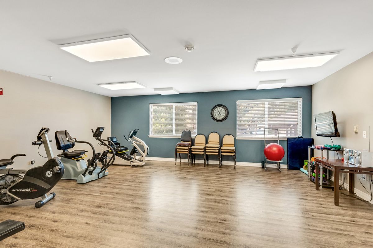 A spacious exercise room with fitness equipment and seating.