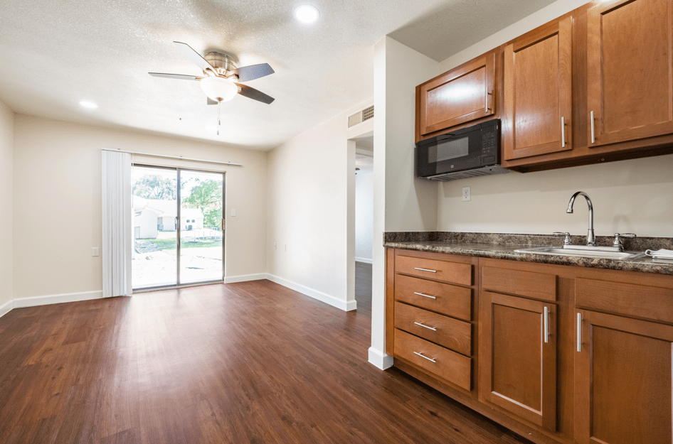 A bright kitchen area with wooden cabinets, a microwave, and sliding glass doors leading outside.