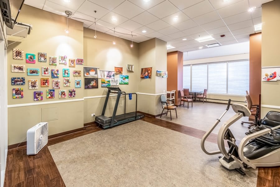 A fitness room with exercise equipment and colorful artwork on the walls.