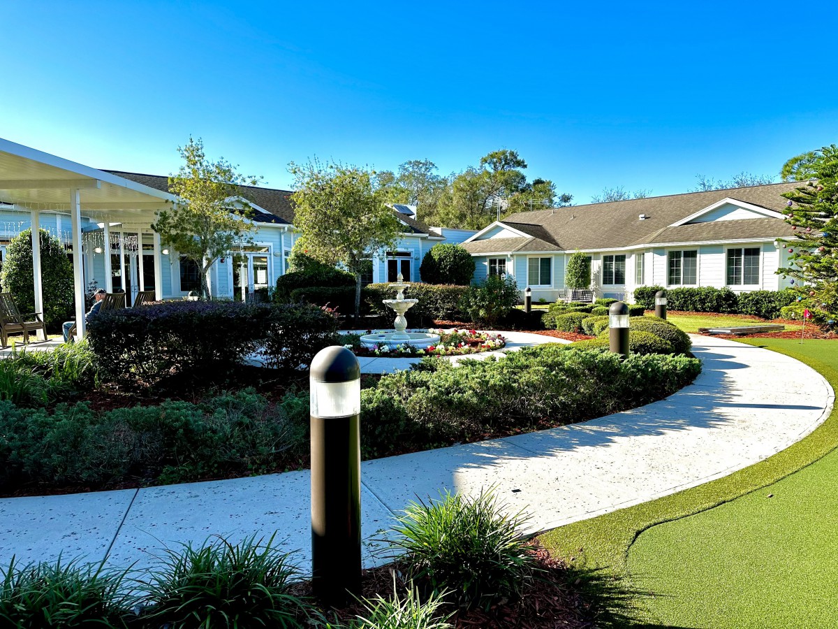 A serene garden with a central fountain surrounded by pathways and buildings.