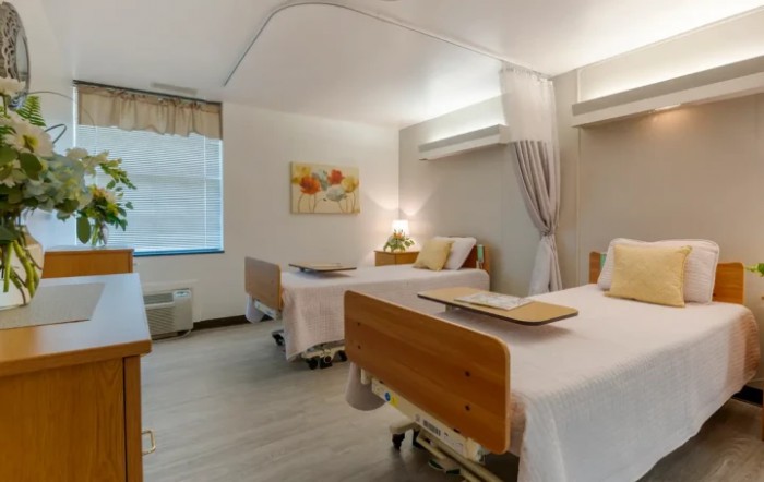 A well-lit hospital room with two patient beds and a clean, organized interior.