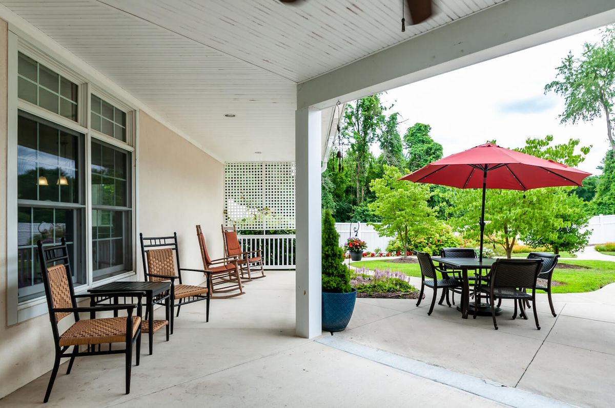 A cozy patio area with outdoor seating, tables, and a view of the garden.