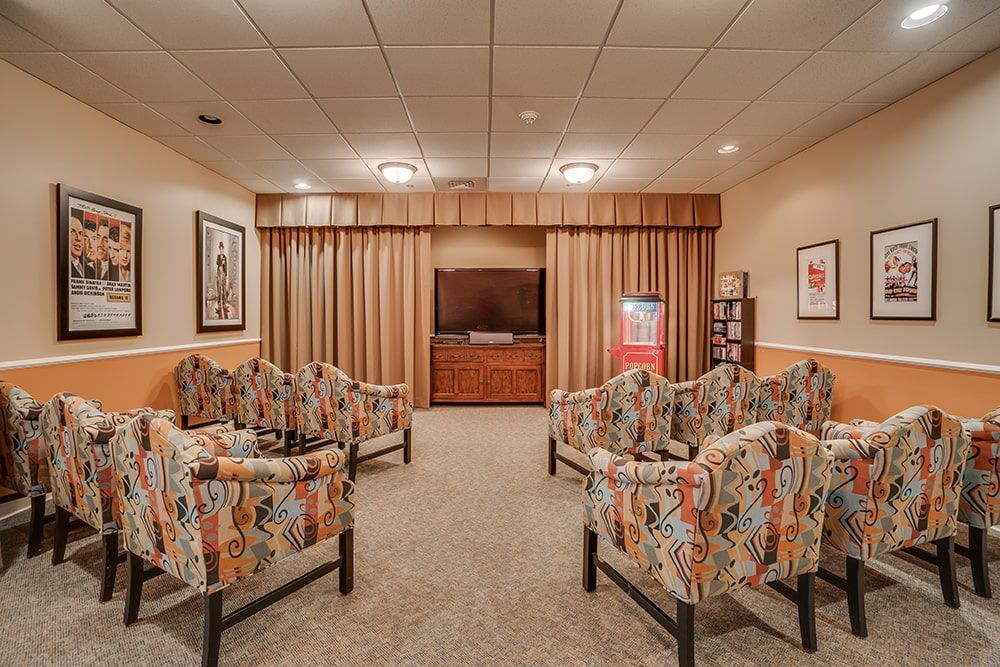 A cozy waiting room featuring patterned chairs, a television, and framed artwork.