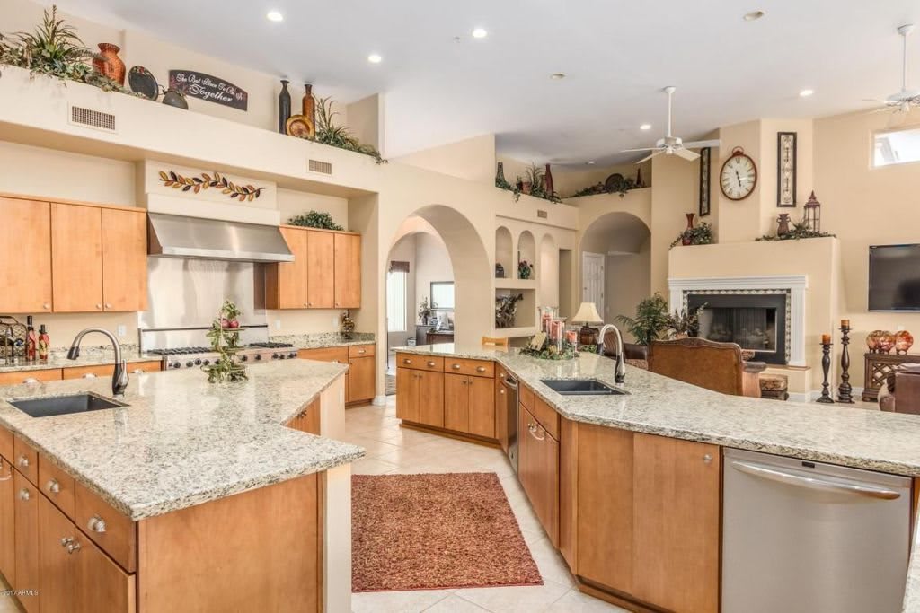 A spacious and modern kitchen with wood cabinets and granite countertops, featuring an open layout and a large island.
