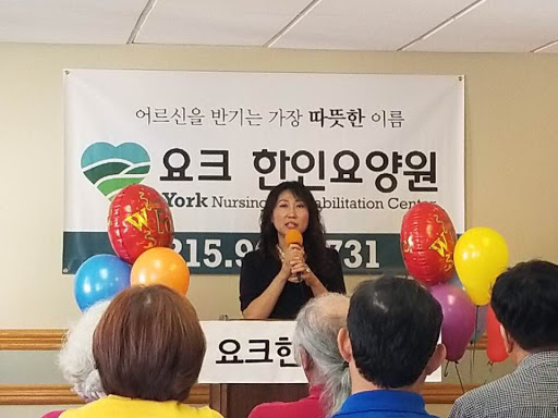 A community event featuring a speaker addressing the audience, with colorful balloons in a welcoming environment.