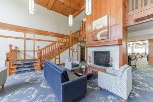 A cozy living room with wood paneling, featuring a fireplace, comfortable seating, and a staircase.