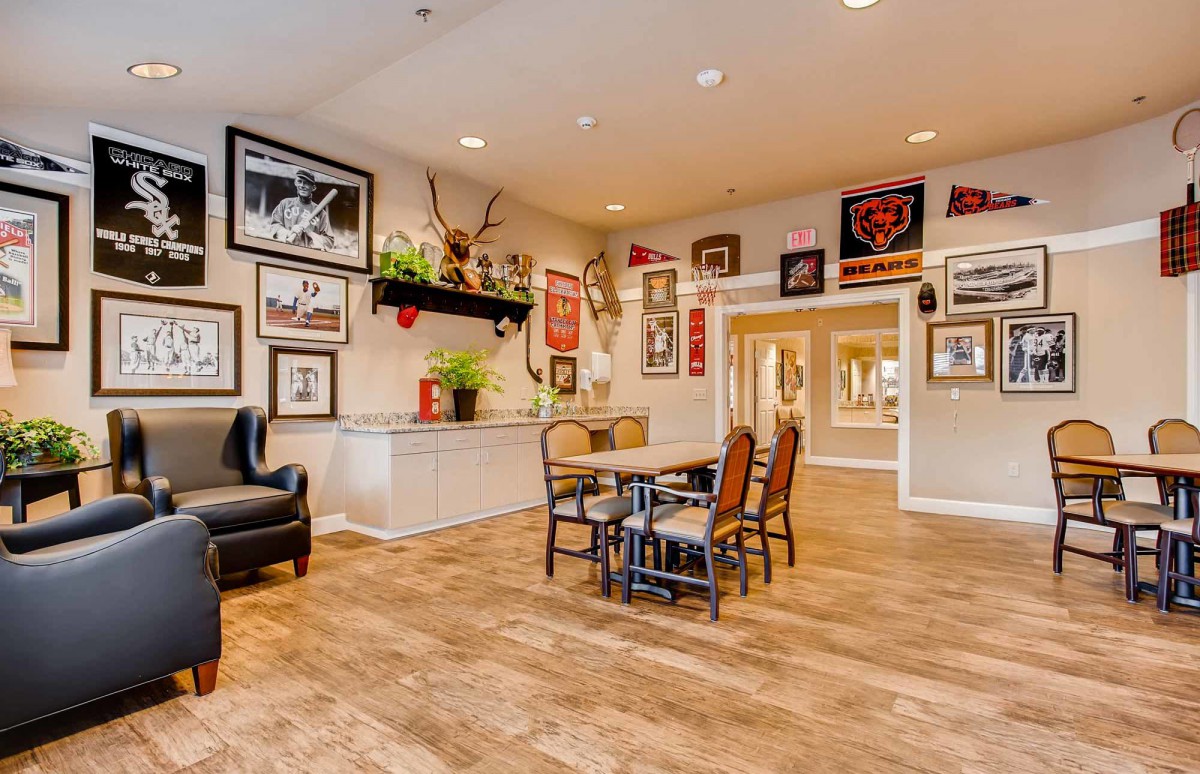 A cozy living room with eclectic decor, featuring framed wall art, plants, and comfortable seating on a wooden floor.