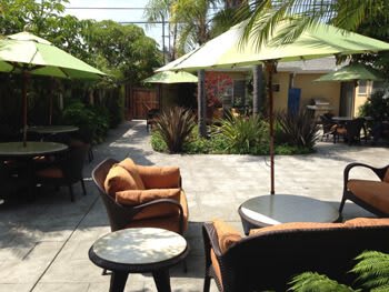 A sunny patio with comfortable garden furniture and large umbrellas providing shade.