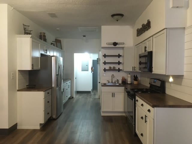 Modern kitchen with white cabinets and hardwood flooring.