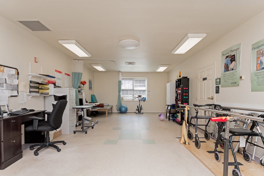 A brightly lit rehabilitation room with various therapy equipment and exercise areas.