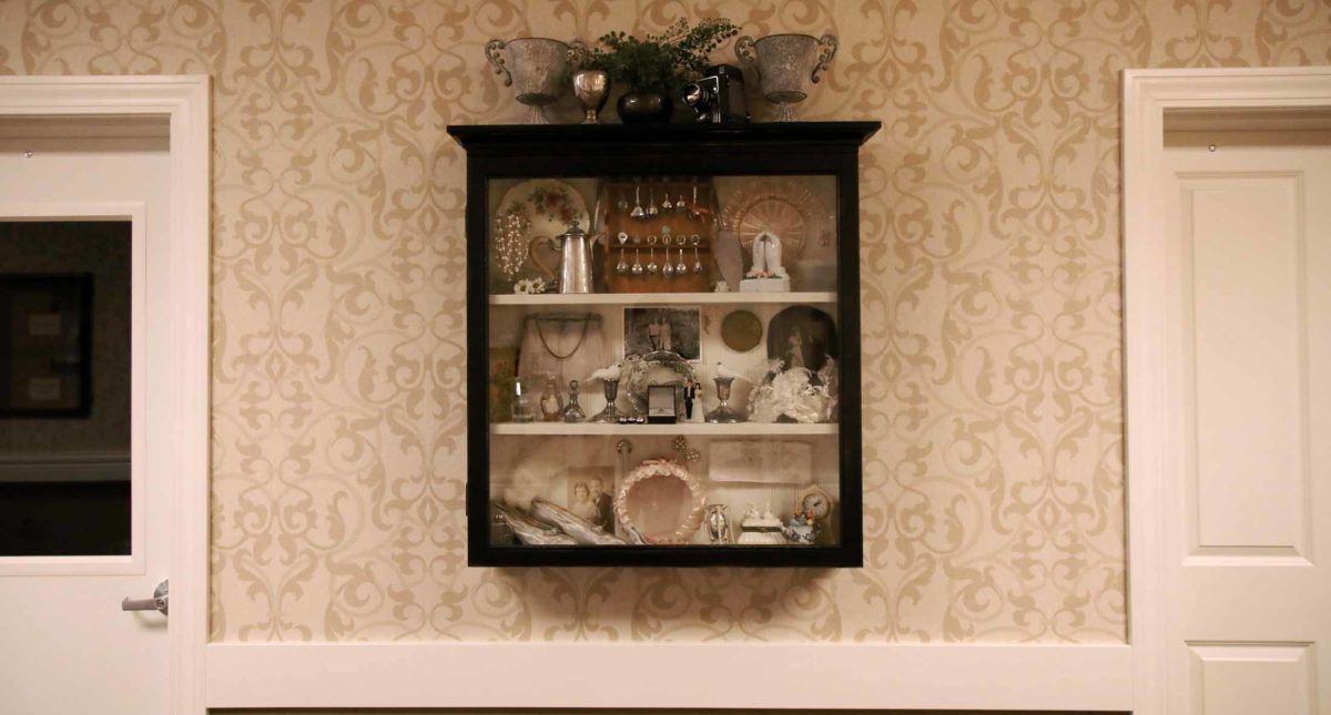 A decorative shadow box mounted on a wall, showcasing an arrangement of memorabilia and antique items.