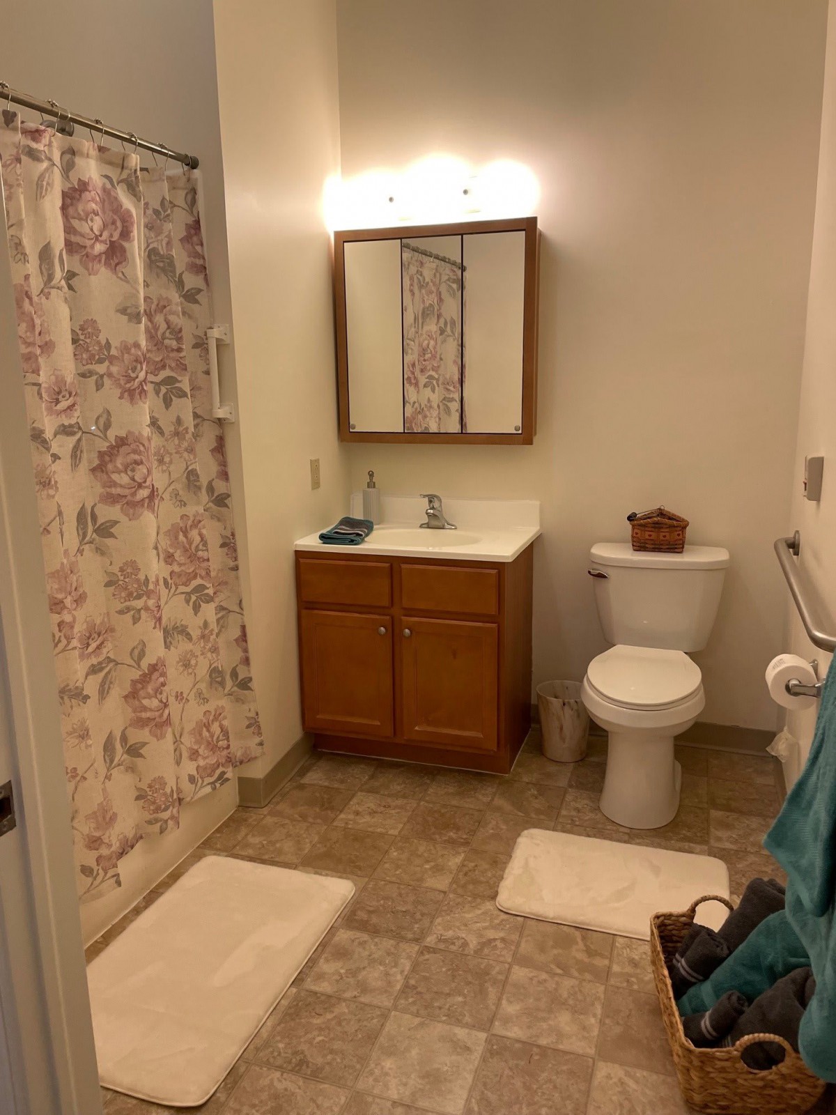 A bathroom with a vanity, toilet, and floral shower curtain.